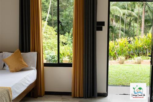 a bedroom with a bed and a large window at Sinharaja Cascade Villa in Deniyaya