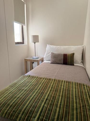 a bedroom with a bed with a green blanket at RQ Costanera Apartments in Santiago
