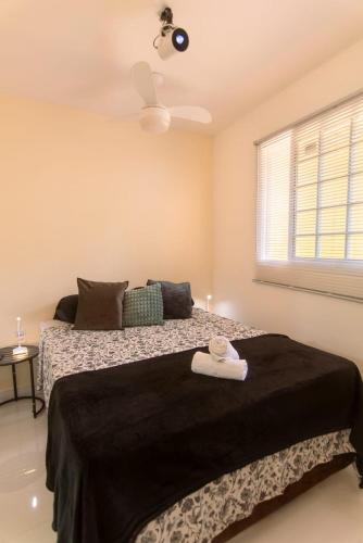 a bedroom with a bed with a black blanket and a window at Golden Pipa House in Pipa