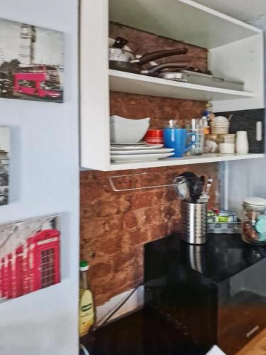 a kitchen with a black counter in a white cabinet at Cosy Studio in Hampton Hill short Walk to Bushy Park with Free Parking and WiFi and Pets welcome in Hampton Hill