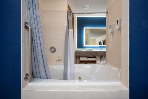 a bathroom with a white tub and a blue shower curtain at All Seasons Resort in Kalkaska