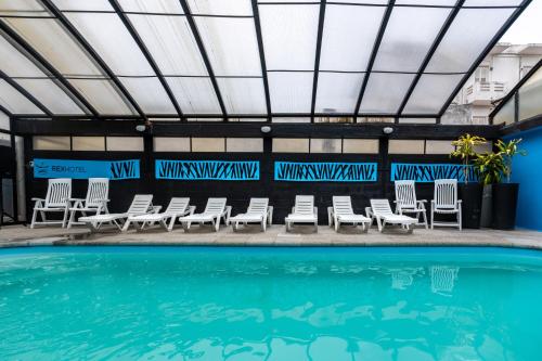 eine Gruppe von Stühlen und ein Swimmingpool in der Unterkunft Hotel Rex in Piriápolis