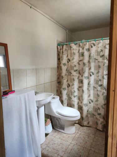 a bathroom with a toilet and a shower curtain at Casa de Coral in Santa Lucía