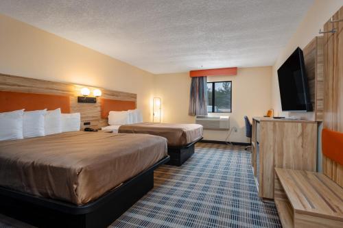 a hotel room with two beds and a flat screen tv at All Seasons Resort in Kalkaska