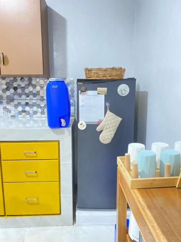 a refrigerator in a kitchen with cups and a table at ZK Homestay in Puerto Princesa City