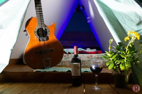 a guitar and a glass of wine next to a tent at Recanto da Filó Serra do Cipó in Serra do Cipo