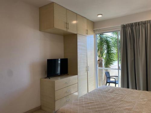 a bedroom with a bed and a tv and a window at Estudio Cerca del mar, en Puerto Aventuras #201 in Puerto Aventuras