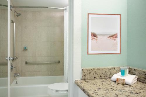 a bathroom with a shower toilet and a picture of the beach at The Beachview Inn Clearwater Beach in Clearwater Beach