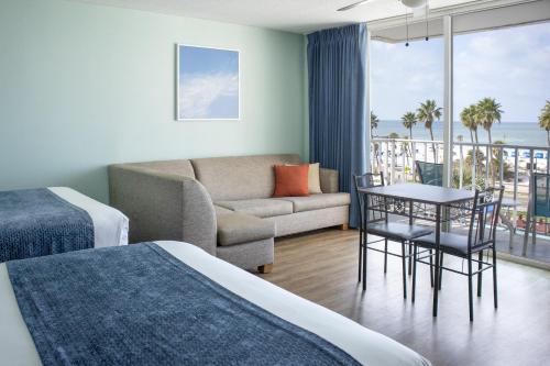 a hotel room with a bed and a couch and a balcony at The Beachview Inn Clearwater Beach in Clearwater Beach
