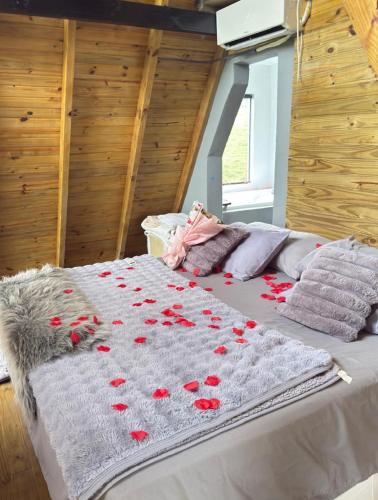 a bed with red rose petals on it at Chalè Aurora do vale in Cobras