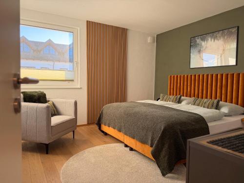 a bedroom with a bed and a chair and a window at "SONNENGRÜN" - Premium Apartments Seekirchen, Balkon in Seekirchen am Wallersee