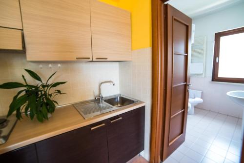 a kitchen with wooden cabinets and a sink and a toilet at Hotel La Maison Jolie in Fiumicino