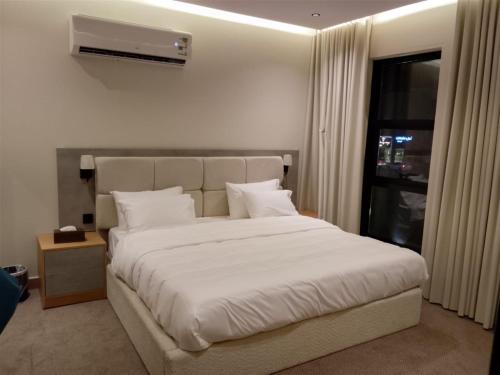 a bedroom with a large white bed and a window at فندق الوعل بالخفجى in Khafji