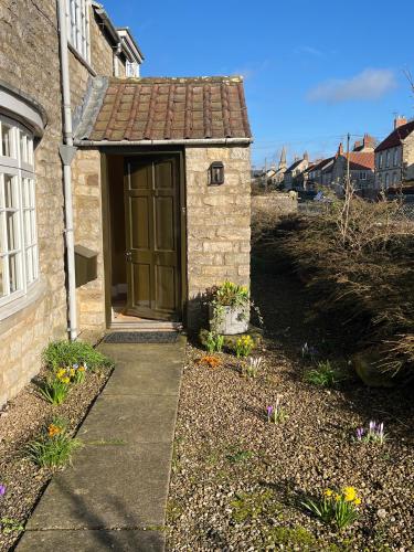 a small brick building with a door in a yard at Woodward Farm House in Appleton le Moors