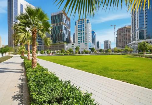 a park with palm trees in a city with tall buildings at CaiCai Homes AG Tower-Business Bay in Dubai