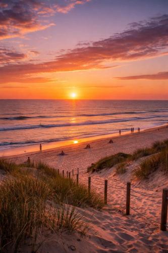 un tramonto sulla spiaggia con persone sulla spiaggia di Le Baleste - Duplex Cosy a Mimizan