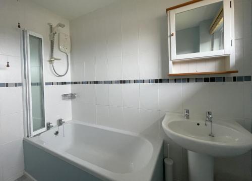 a bathroom with a sink and a tub and a mirror at 16 Manesty View in Keswick