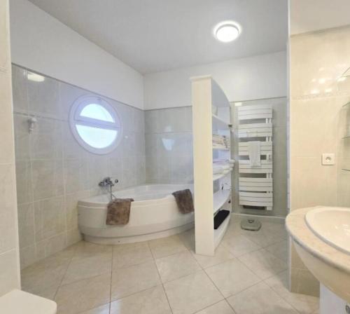 a white bathroom with a tub and a sink at Enjoy 5Bdr villa pool and BBQ in Saint-Raphaël