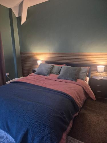 a bedroom with a large bed with two lamps at Sleep Eat Repeat Apartment in Macclesfield