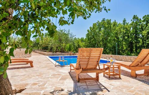 two chairs and a table next to a swimming pool at Holiday Home Pearl in Stone in Imotski
