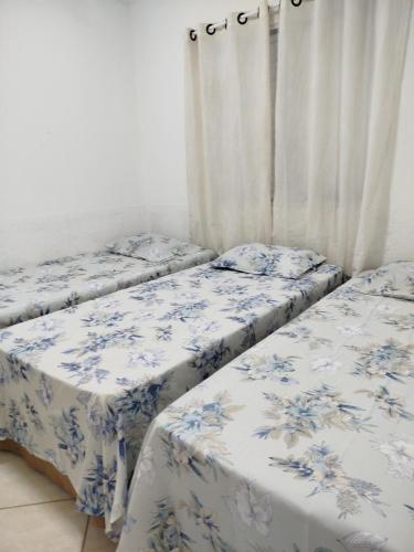 two beds in a room with blue and white sheets at Casa Aconchego in São Carlos