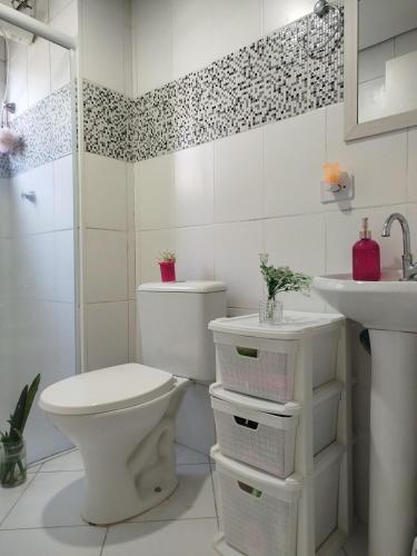 a white bathroom with a toilet and a sink at Casa Aconchego in São Carlos