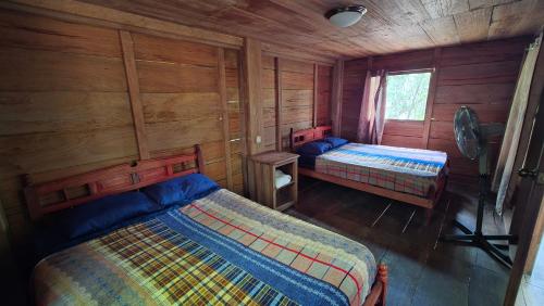 a bedroom with two beds in a wooden cabin at Cabaña Tu´ur in Lacanjá