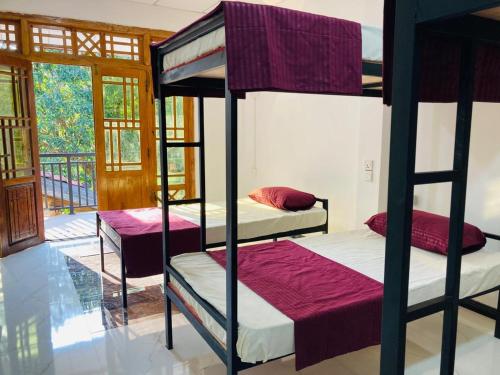 two bunk beds in a room with a balcony at Ashi Hostel Sigiriya in Sigiriya