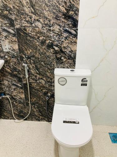a white toilet in a bathroom with a wall at Ashi Hostel Sigiriya in Sigiriya