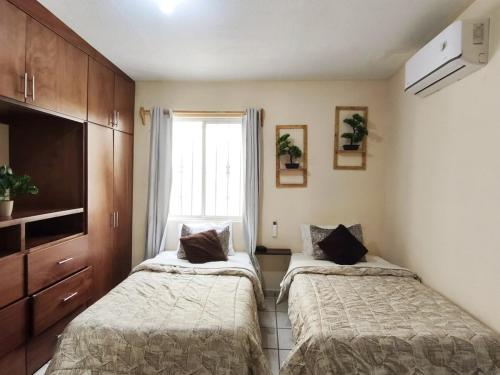 two beds in a small room with a window at Bonsai House in Ramos Arizpe