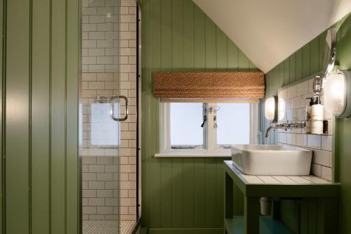 a green bathroom with a sink and a window at Bel and The Dragon-Cookham in Cookham