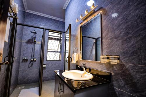 a bathroom with a sink and a shower and a mirror at Taye Apartments in Entebbe