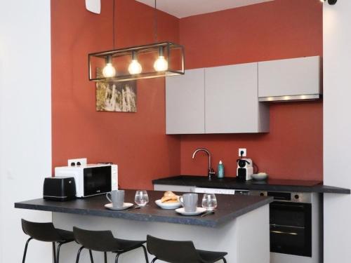 a kitchen with white cabinets and a counter with chairs at Notre Dame de Senlis by La boite en Plus in Senlis