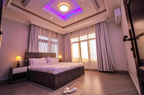 a bedroom with a large bed with a purple ceiling at Taye Apartments in Entebbe