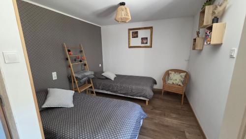 a small bedroom with two beds and a chair at Gîte L'échappée Bleue in Saint-Germain-du-Plain