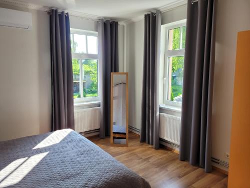 a bedroom with a mirror and two windows at Apartamenti HUGO in Valmiera
