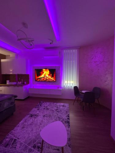 a living room with purple lighting and a fireplace at Studio Apartman Kostić in Gracanica