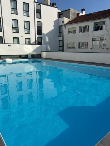 a large blue swimming pool in front of two buildings at Apartamento "Playa de Sada" in Sada