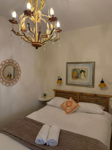a chandelier hanging over a bed with towels on it at נופש בפינה in Rosh Pinna