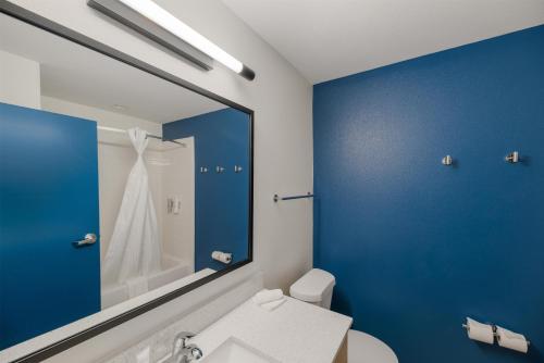a bathroom with a white toilet and a blue wall at Spark by Hilton Midland South in Midland