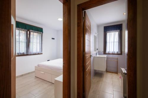 a bedroom with a bed and a bathroom with a sink at Villa Senda Llanes – Jardín, Terraza y Playa Cerca in Llanes