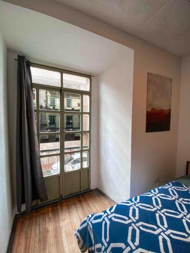 a bedroom with a bed and a large window at Cossy studio apartment in downtown in Cuenca