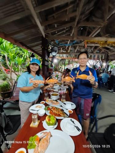a group of people standing around a table with food at Koh Phaluay Eco Resort in Ko Phaluai
