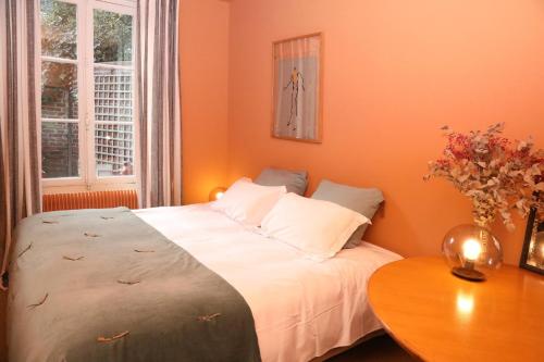 a bedroom with orange walls and a bed with a table at La Maison des Rues Pavées avec jardin by La Boîte En Plus in Senlis