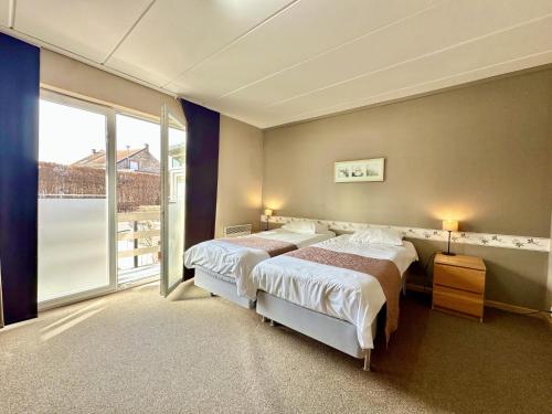 a bedroom with two beds and a large window at Le Petit Vallon in Polleur