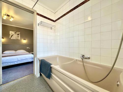 a bathroom with a tub and a bed in a room at Le Grand Vallon in Polleur