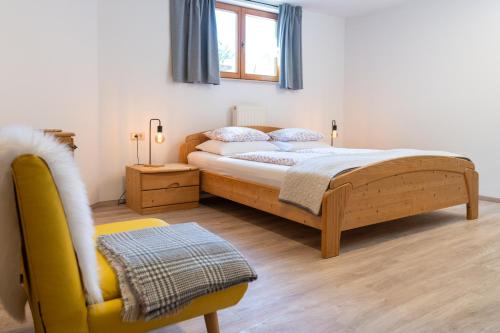 a bedroom with a bed and a yellow chair at Apartments Rožič Bohinj in Bohinj