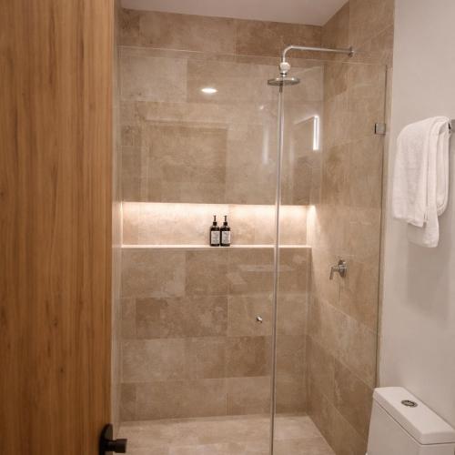 a shower with a glass door in a bathroom at NEW 2 bed swim-up, gril with jacuzzi Aldea Zamá in Tulum