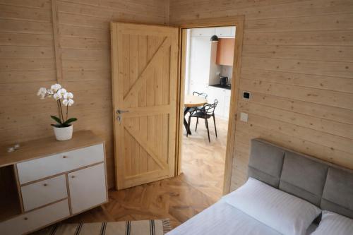 a room with a bed and a door with a table at Przylesie Domki in Wysoczany