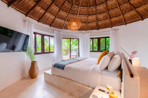 a bedroom with a bed and a tv and windows at Azulea Bacalar Hotel & Spa - Lagoon Front in Bacalar